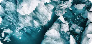 A large iceberg floats in vibrant blue water, showcasing its majestic size and icy texture against the serene backdrop.